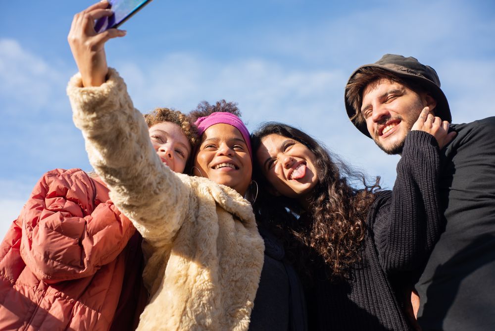 Un grupo de amistades diversas se hace un selfie al sol.